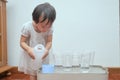 Cute Asian toddler girl having fun playing with water table at home, Wet Pouring Montessori Preschool Practical Life Activities,