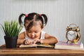 Cute asian toddler reading a book with alarm clock Royalty Free Stock Photo