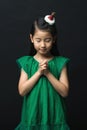 Cute Asian woman praying for Christmas with headdress on black background and gathering two hands Children