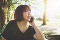 Cute asian woman smiles and talking on mobile phone while sitting in park spring day. Royalty Free Stock Photo