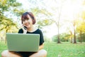 Cute asian woman smiles and talking on mobile phone while sitting in park spring day. Royalty Free Stock Photo