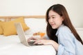 Cute asian woman using computer laptop to work from home in bedroom with breakfast meal in morning. Royalty Free Stock Photo