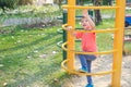 Cute Asian 3 years old toddler baby boy child having fun trying to climb on climbing frame at outdoor playground Royalty Free Stock Photo