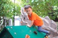 Cute Asian toddler boy having fun trying to climb on artificial boulders at playground on nature