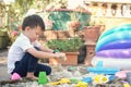 Cute Asian toddler boy playing with sand alone at home, Kid playing with sand toys in urban home garden , Montessori education, Royalty Free Stock Photo