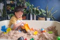 Cute Asian young boy playing with sand alone Kid playing with sand toys in urban home garden , Montessori education, Creative play Royalty Free Stock Photo