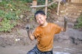 Cute Asian young schoolboy having fun playing and exploring in muddy puddles alone, Little kid getting dirty in mud pond at the