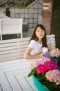 Cute asian young woman in summer cafe outdoors. girl In white T-shirt, with long hair in simple light cozy interior of restaurant Royalty Free Stock Photo