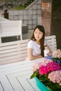 Cute asian young woman in summer cafe outdoors. girl In white T-shirt, with long hair in simple light cozy interior of restaurant Royalty Free Stock Photo