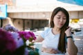 Cute asian young woman in summer cafe outdoors. girl In white T-shirt, with long hair in simple light cozy interior of restaurant Royalty Free Stock Photo