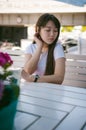 Cute asian young woman in summer cafe outdoors. girl In white T-shirt, with long hair in simple light cozy interior of restaurant Royalty Free Stock Photo