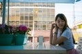 Cute asian young woman in summer cafe outdoors. girl In white T-shirt, with long hair in simple light cozy interior of restaurant Royalty Free Stock Photo