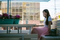 Cute asian young woman in summer cafe outdoors. girl In white T-shirt, with long hair in simple light cozy interior of restaurant Royalty Free Stock Photo