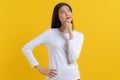 Cute asian young woman in white casual dress looking up and thinking / imagination isolated on yellow background in studio Royalty Free Stock Photo