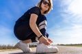 cute athlete woman tying her shoes during a workout on a country road Royalty Free Stock Photo