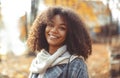 Cute autumn close up portrait of young smiling happy african american woman with curly hair enjoying walk in park in fall season Royalty Free Stock Photo