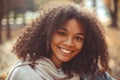 Cute autumn close up portrait of young smiling happy african american woman with curly hair enjoying walk in park in fall season Royalty Free Stock Photo