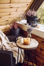 Cute autumn home decor arrangement. Tiny wooden cabin balcony with heather flowers in pot. Royalty Free Stock Photo