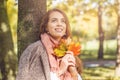 Cute autumn woman holding yellow maple leaf outdoors. Romantic girl in fall park Royalty Free Stock Photo