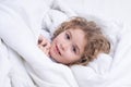 Cute awaking child in bed, bedtime, childhood and growth kids concept, close-up indoor portrait.