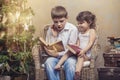 Cute babies boy and girl in a chair reading a book in a interior Royalty Free Stock Photo