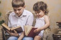 Cute babies boy and girl in a chair reading a book in a interior Royalty Free Stock Photo