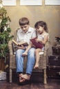 Cute babies boy and girl in a chair reading a book in a interior Royalty Free Stock Photo