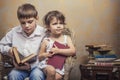 Cute babies boy and girl in a chair reading a book in a interior Royalty Free Stock Photo