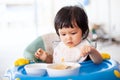 Cute baby asian child girl eating healthy food by herself Royalty Free Stock Photo