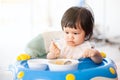 Cute baby asian child girl eating healthy food by herself Royalty Free Stock Photo