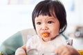 Cute baby asian child girl eating healthy food by herself Royalty Free Stock Photo