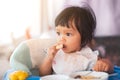 Cute baby asian child girl eating healthy food by herself Royalty Free Stock Photo