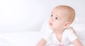 Cute baby with beautiful brown eyes lying in white bed Royalty Free Stock Photo