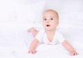 Cute baby with beautiful brown eyes lying in white bed Royalty Free Stock Photo