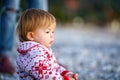 A cute baby in a beautiful sweater on the shore of the winter sea. Beautiful child in nature. The kid sits in profile on a beach