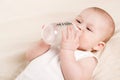 Cute baby with a bottle of milk on a beige blanket Royalty Free Stock Photo