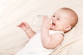 Cute baby with a bottle of milk on a beige blanket Royalty Free Stock Photo