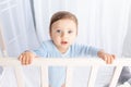 Cute baby boy with big blue eyes in the crib in the nursery, portrait Royalty Free Stock Photo