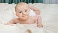 Cute baby boy with blue eyes lying on bed and crawling towards camera. Royalty Free Stock Photo