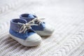 Cute baby boy blue sneakers on white knitted fabric Royalty Free Stock Photo