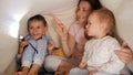 Cute baby boy with brother and mother playing with flashlight and shadows under blanket in bed. Family having time together, Royalty Free Stock Photo