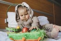 Cute baby boy in the bunny costume playing with the basket with colorful easter eggs. Easter egg hunt and baby development Royalty Free Stock Photo