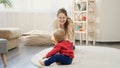 Cute baby boy crawling on floor to his mother and throwing a ball. Baby development, family playing games, making first steps, Royalty Free Stock Photo