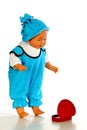 Cute baby boy doll in turquoise jumpsuit and hat with red gift box Royalty Free Stock Photo