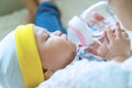 Cute baby boy drinking water from bottle with his mom. Hand of asian young woman holding bottle with water while feeding Royalty Free Stock Photo