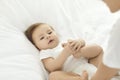 Cute baby boy or girl is lying in an infant bed and looking at his or her mother Royalty Free Stock Photo