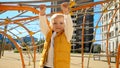 Cute baby boy hanging on rope at playground. Children playing outdoor, kids outside, summer holiday and vacation Royalty Free Stock Photo