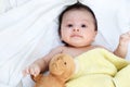 The cute baby boy is happy with yellow blanket and doll bear lovely friend on the white bed Royalty Free Stock Photo