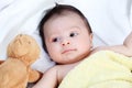 The cute baby boy is happy with yellow blanket and doll bear lovely friend on the white bed Royalty Free Stock Photo