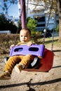 Cute baby boy having fun on outdoor playground. Toddler activities. Serious baby swinging on swing Royalty Free Stock Photo